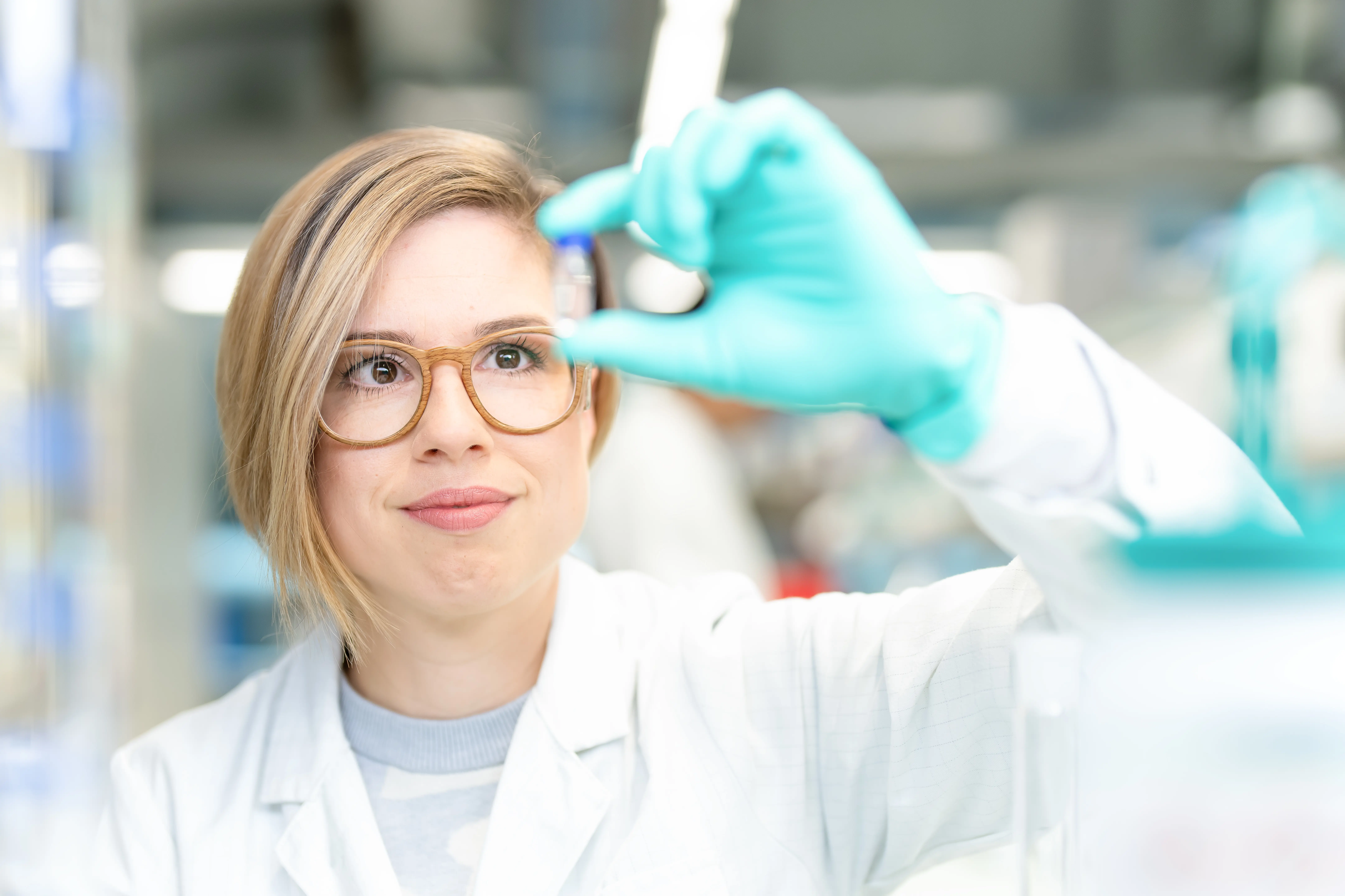 Eine junge Frau prüft im Labor eine Substanz.